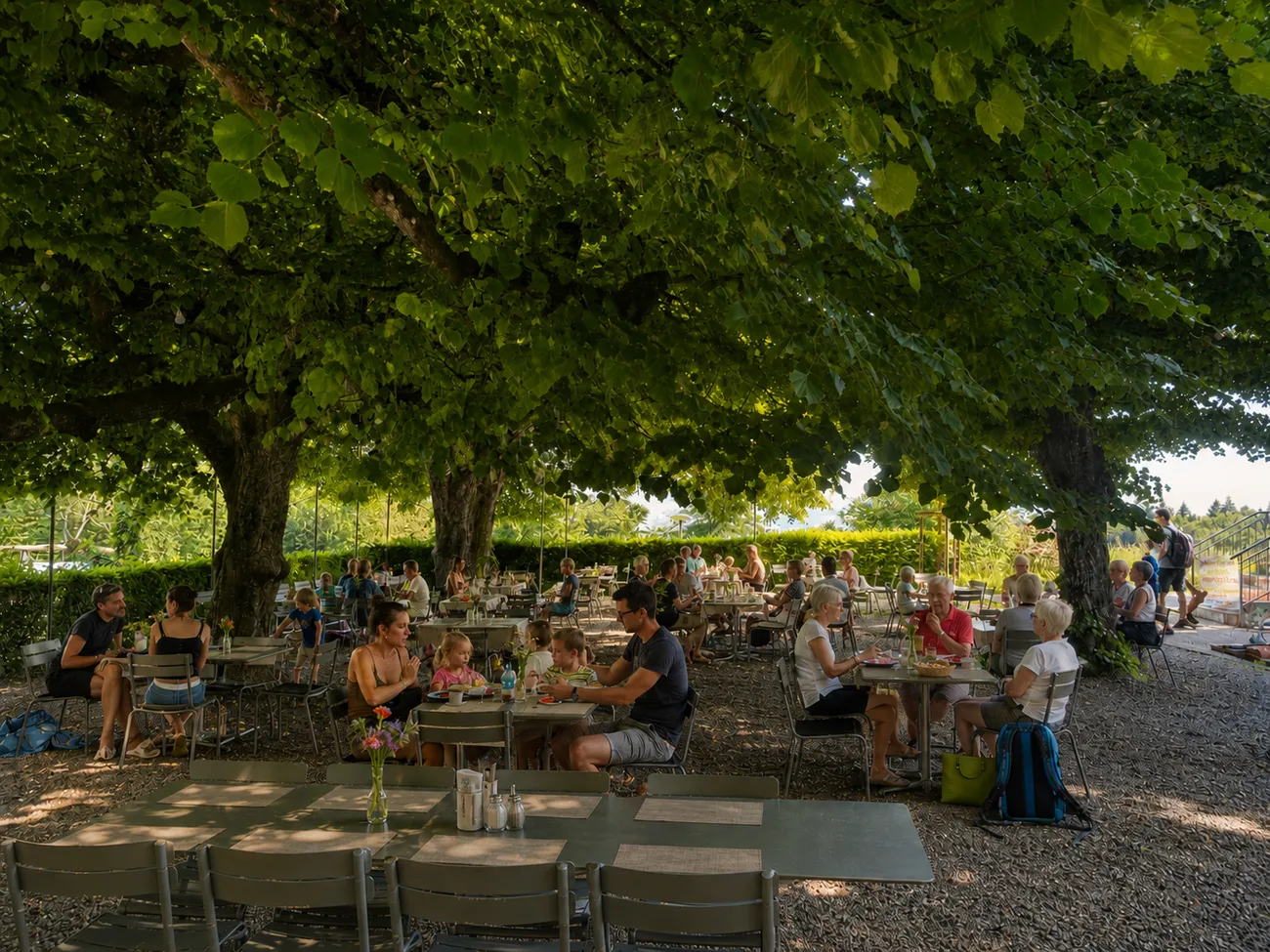 Gartenwirtschaft unter den Linden mit Gästen an einem Sommertag