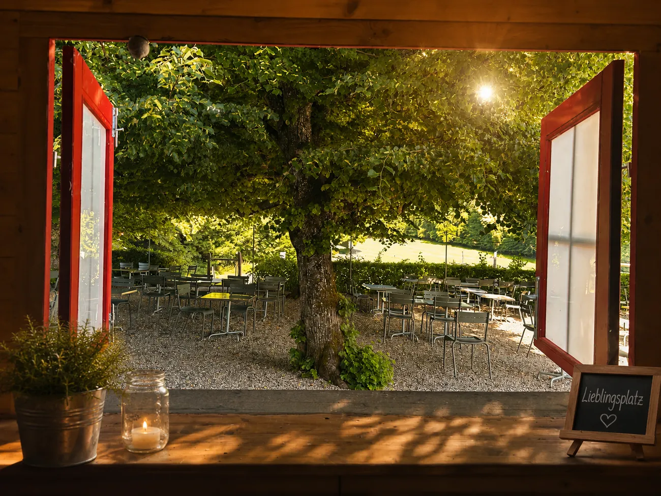 Blick aus der Buvette in den Garten mit „Lieblingsplatz“-Tafel